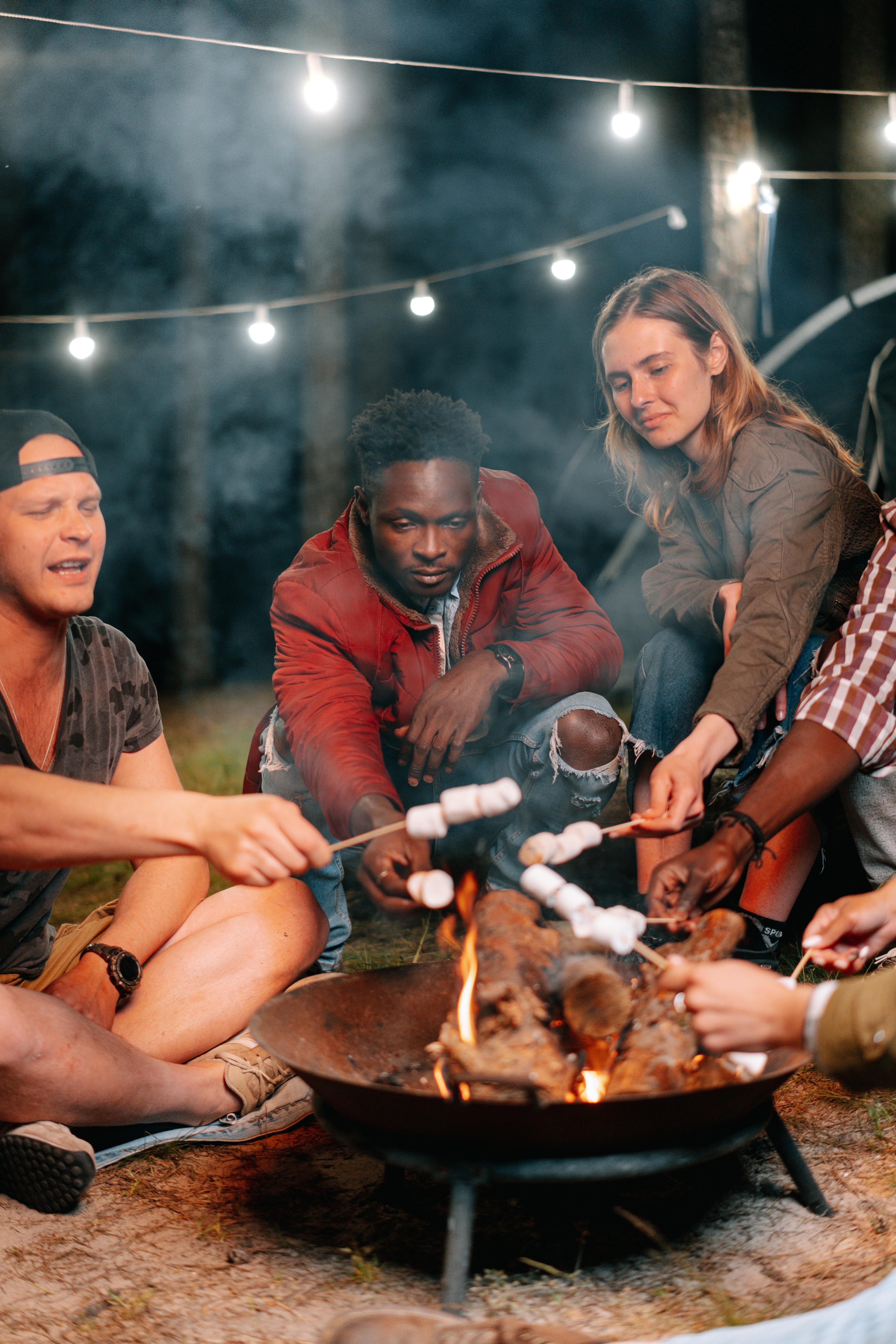 Friends heating up marshmallows round a fire